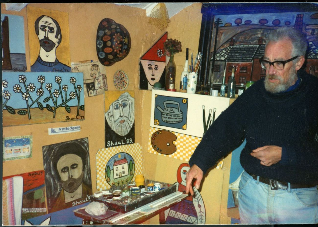Terry Shaul in the corner of his cottage, surrounded by paintings and drawings